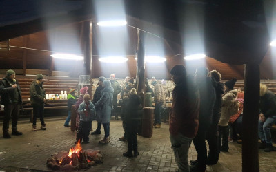 Uczestnicy zgromadzeni pod wiatą przy ognisku słuchają opowieści o sowach, które opowiada Kamil Taras z Oddziału w Chełmie